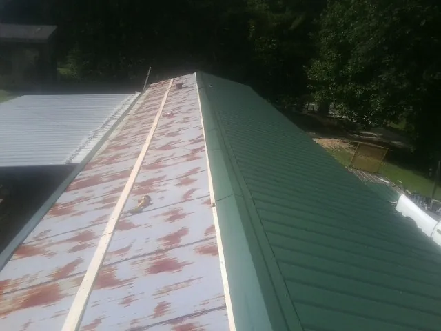 Old rusted panels beside newly installed green metal roofing — Wind Damage Roof Repair by Roofing Brothers in Pleasant Shade