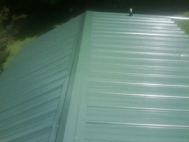 New green metal panels meeting at the ridge of a roof — Flat Roof Repair work by our crew in Pleasant Shade
