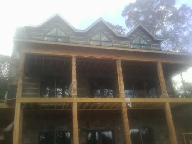 Dormers and porch framing on a large log home under construction — Roof Coating work by our crew in Pleasant Shade