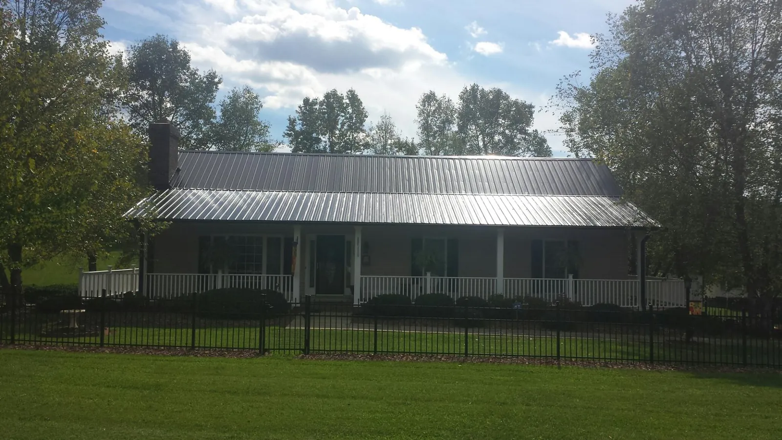 Gray metal roof on a brick ranch with a full width front porch — Gutter Guard Installation work by our crew in Pleasant Shade