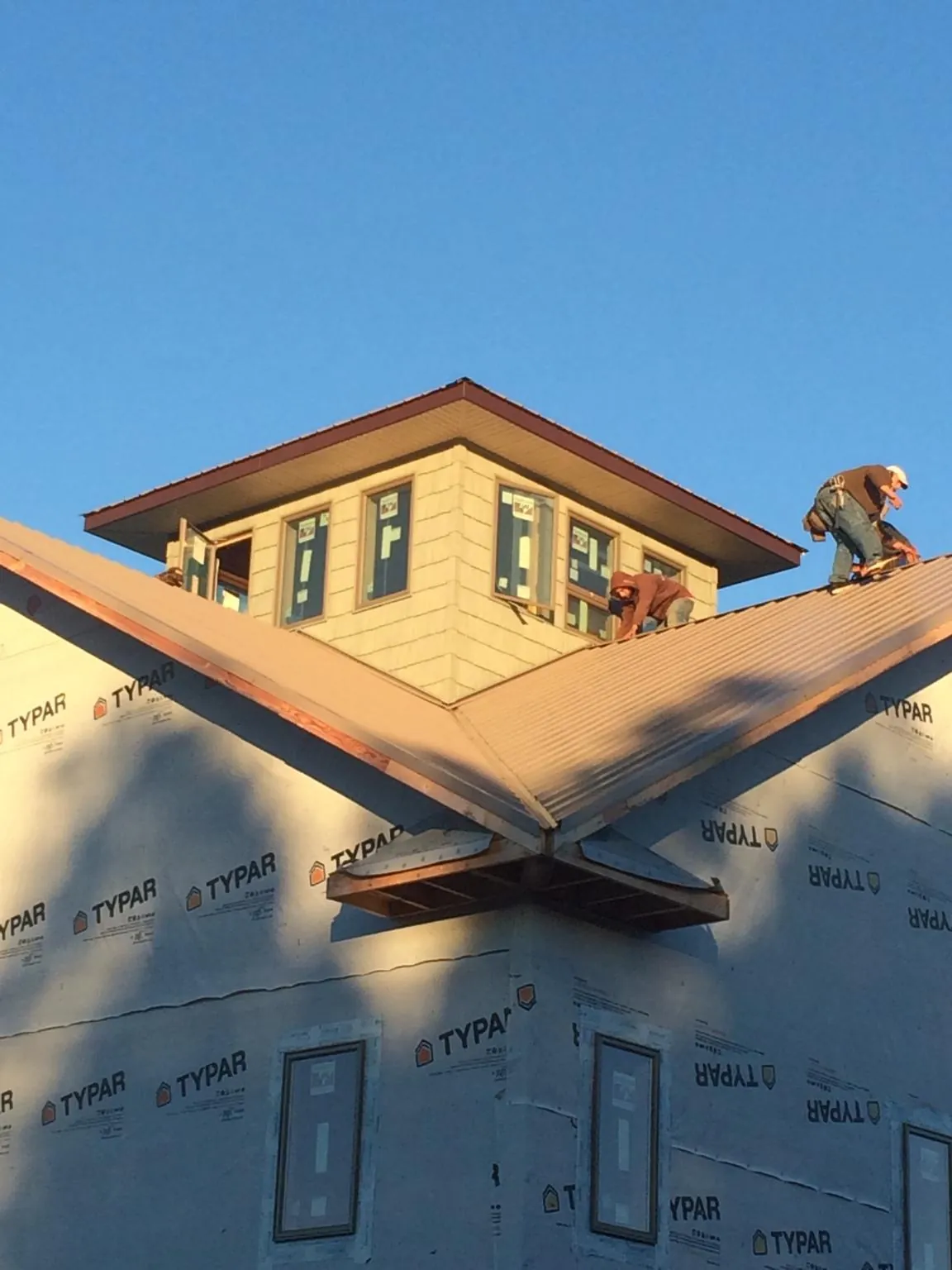 Roofers working around a rooftop cupola on a new metal roof at sunset — Roof Waterproofing in Pleasant Shade by Roofing Brothers